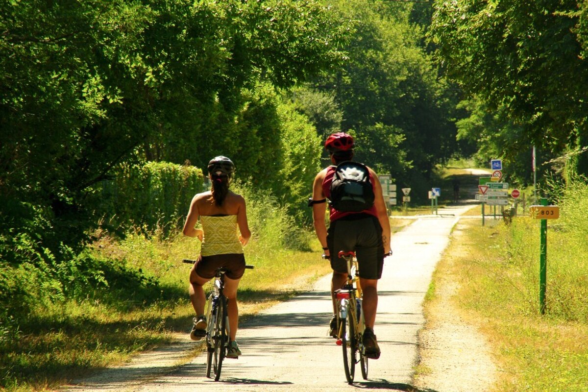 Two people riding bicycles down a path with a sign that says ' a ' on it