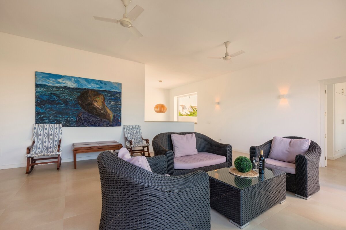 A living room with wicker furniture and a painting on the wall