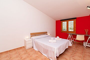 A bedroom with a white bed and a red wall