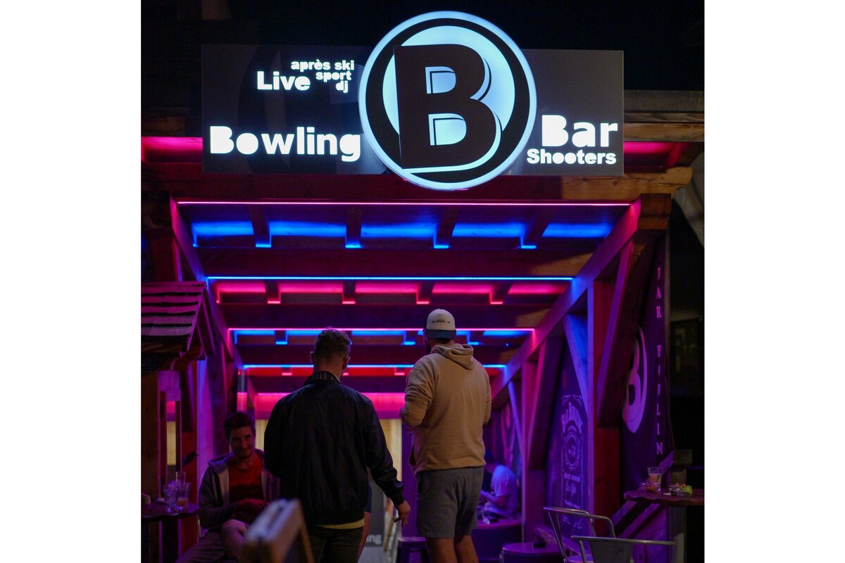 A sign for bowling bar shooters is lit up at night