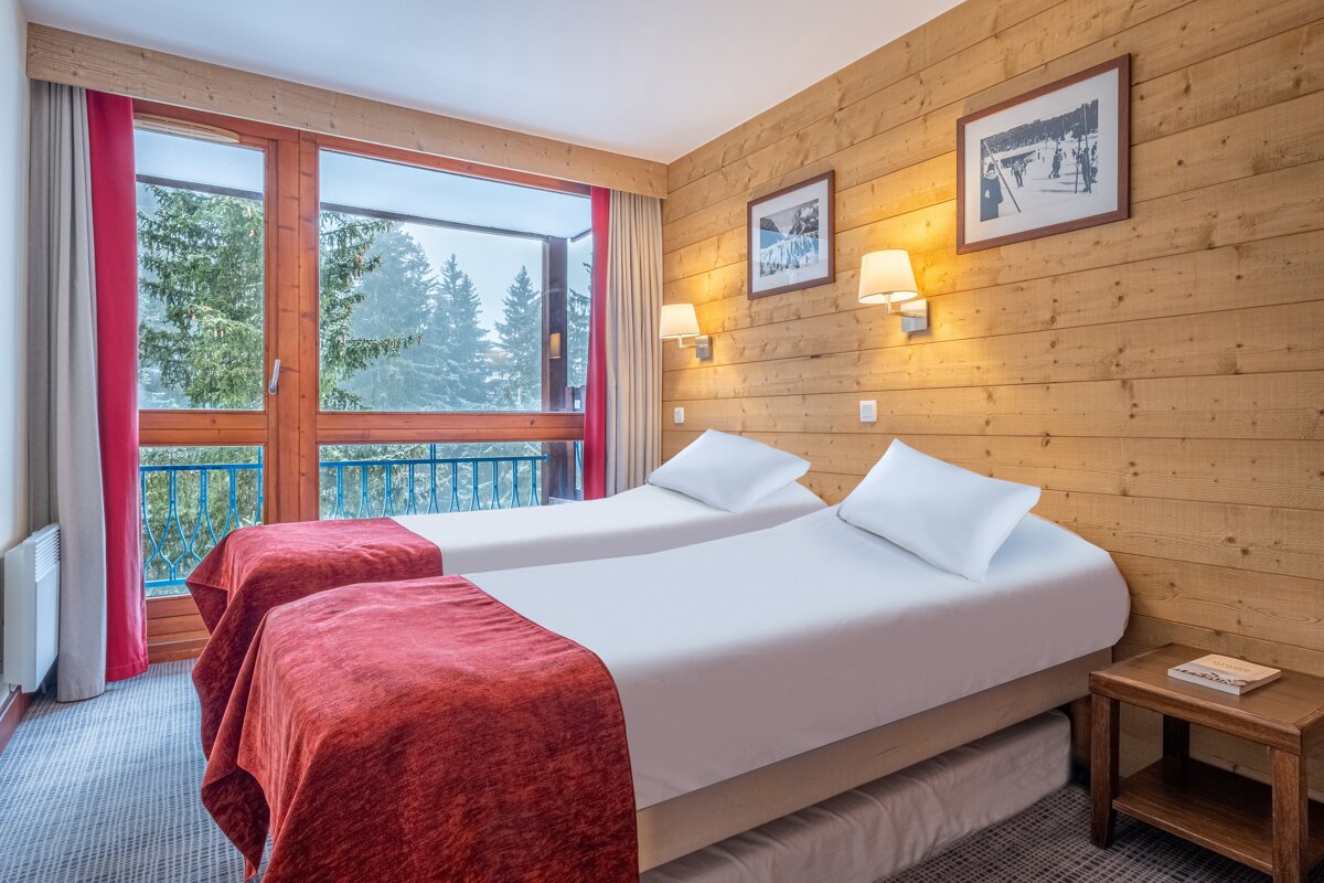 A hotel room with two beds and two pictures on the wall