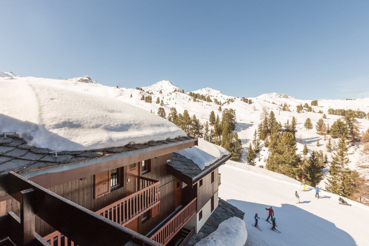 Skiers on a snowy slope with a building in the foreground