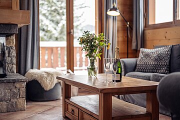 A bottle of champagne sits on a wooden coffee table