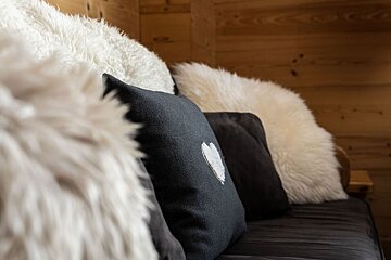 A black pillow with a heart on it sits on a couch