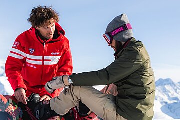 A man wearing a rossignol jacket talks to another man