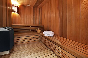 A wooden sauna with a bucket and towels on the bench