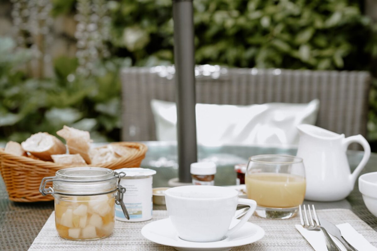 A table with a cup of coffee and a jar of jam
