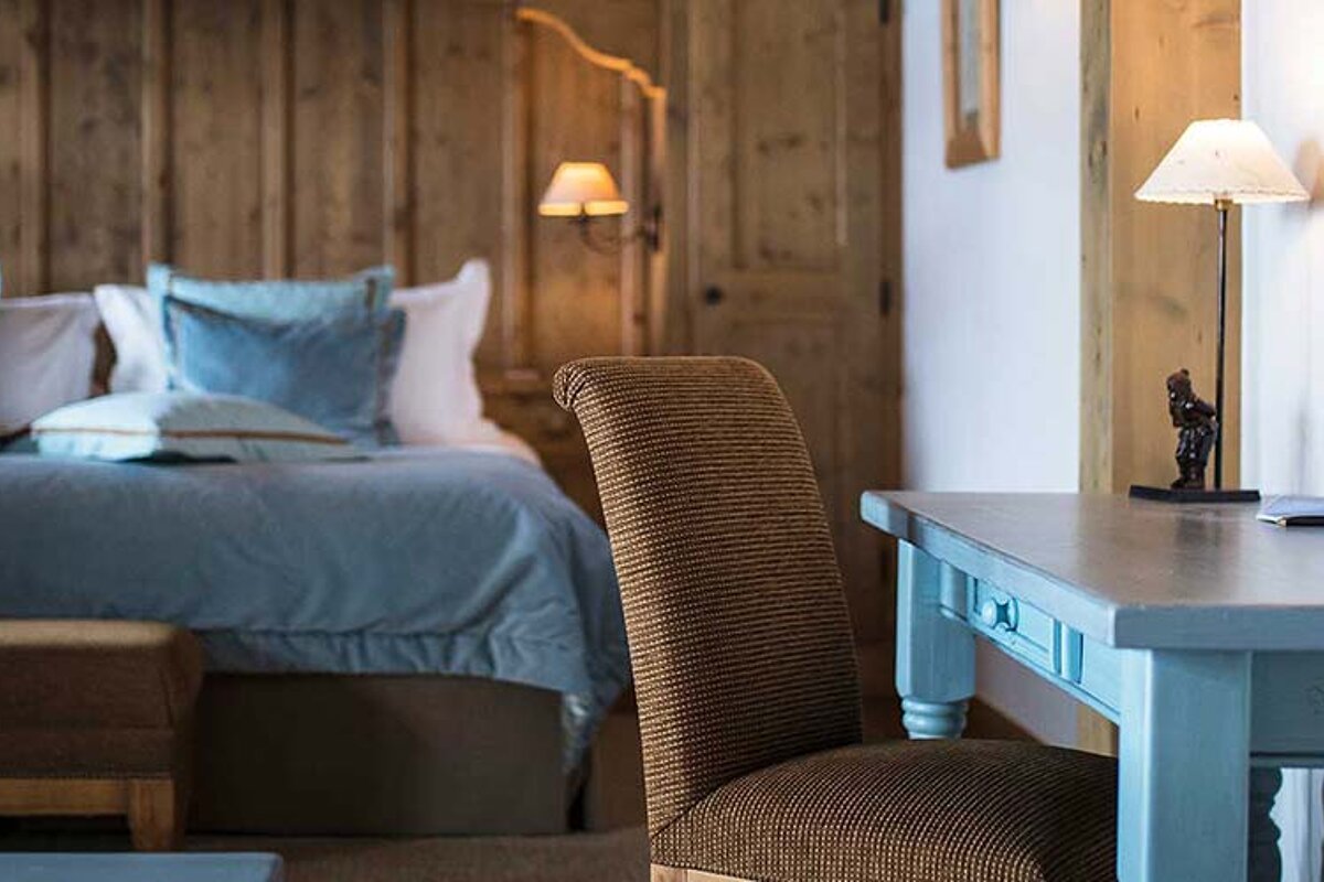 A bedroom with a desk and chair in front of a bed