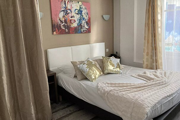A bedroom with a painting of marilyn monroe on the wall above the bed