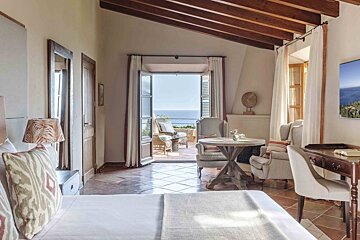 A bedroom with a table and chairs and a view of the ocean