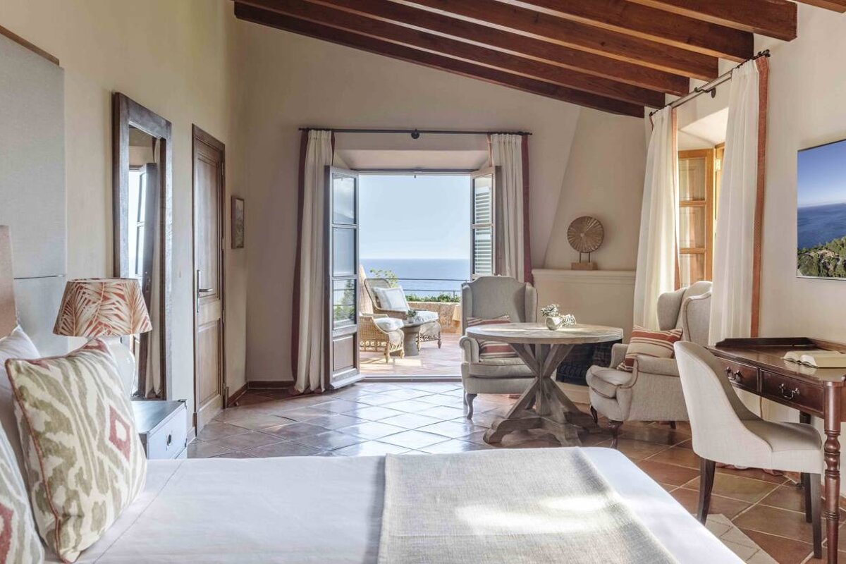 A bedroom with a table and chairs and a view of the ocean