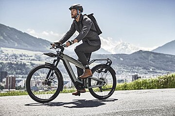 A man wearing a helmet is riding an electric bike