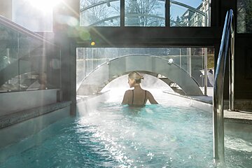 A woman is swimming in a pool under a bridge