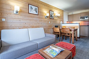 A living room with a couch and a table with a magazine on it that says keep calm
