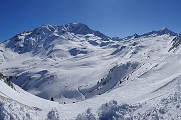 A snowy mountain with a blue sky in the background