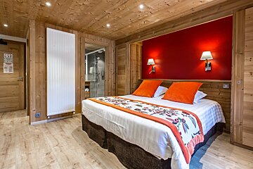 A hotel room with a bed and a red wall