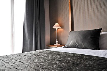 A bedroom with a bed and a lamp on the nightstand