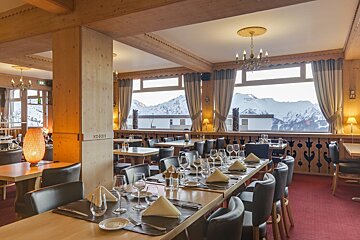 A dining room with tables and chairs and a large window with mountains in the background