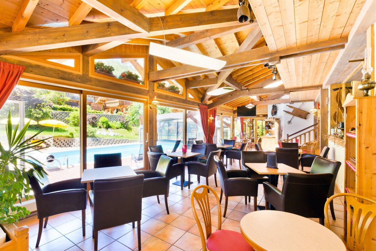 A restaurant with tables and chairs and a pool in the background
