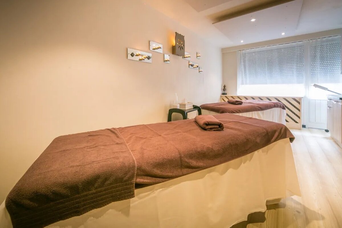 Two massage tables in a room with a clock on the wall above them