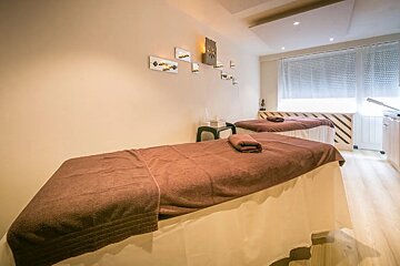 Two massage tables in a room with a clock on the wall above them