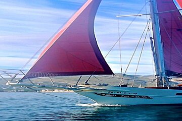 A sailboat with a red sail is floating on the water