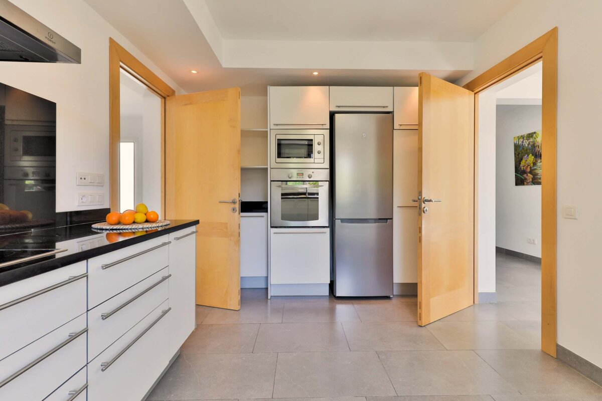 A kitchen with white cabinets and a stainless steel refrigerator