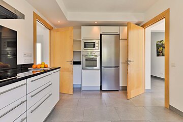 A kitchen with white cabinets and a stainless steel refrigerator