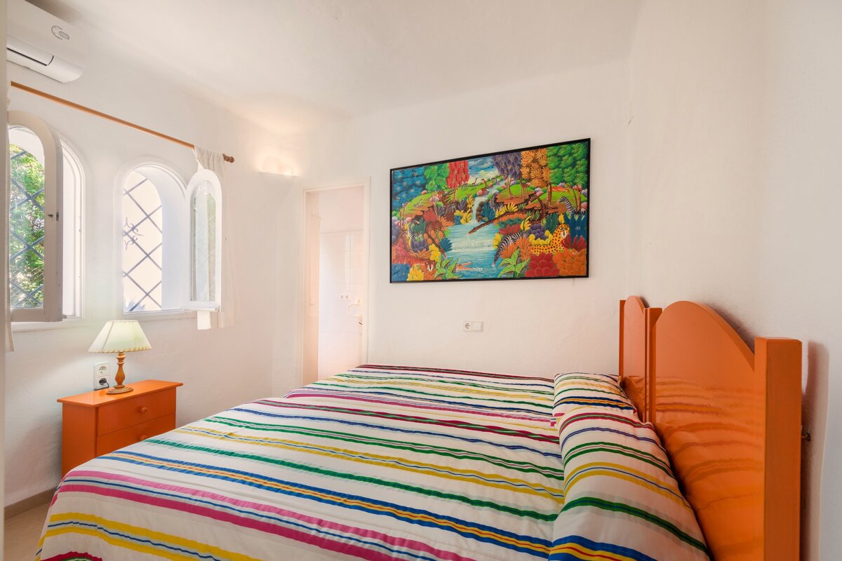 A bedroom with a painting on the wall above the bed