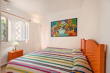 A bedroom with a painting on the wall above the bed