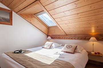 A bedroom with a bed and two pillows with hearts on them