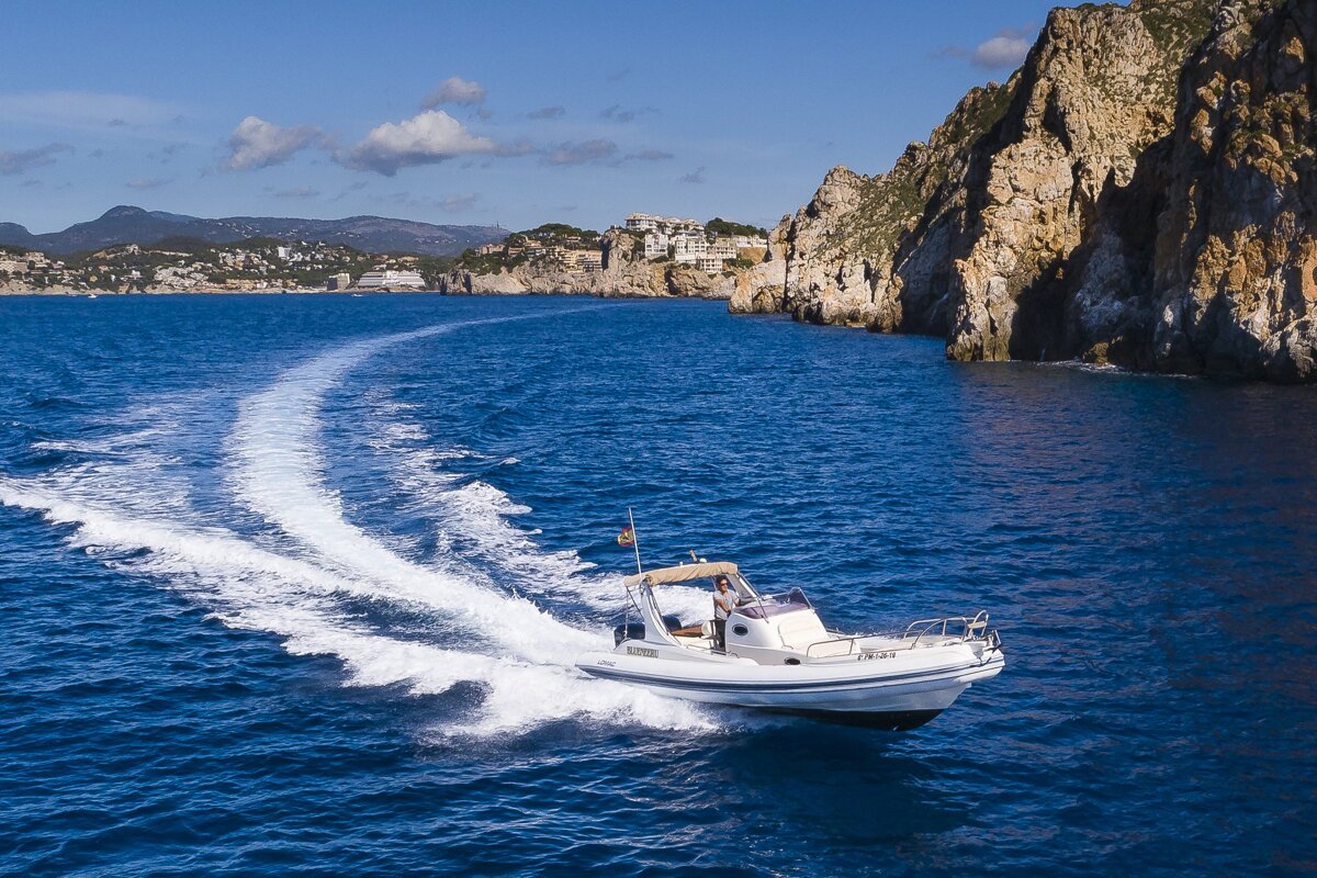 A boat is floating on the water near a cliff