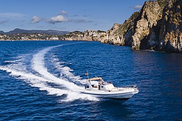 A boat is floating on the water near a cliff