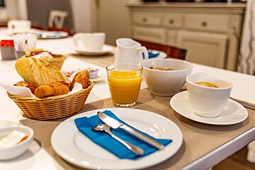 A table with a basket of bread and a glass of orange juice