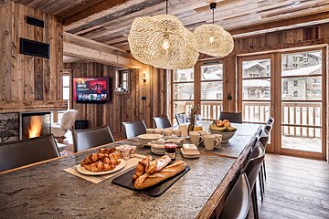 A dining room table with a tray of croissants on it