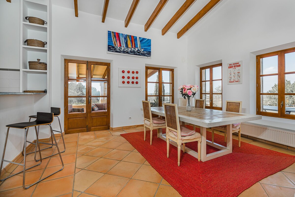 A dining room with a table and chairs and a painting on the wall
