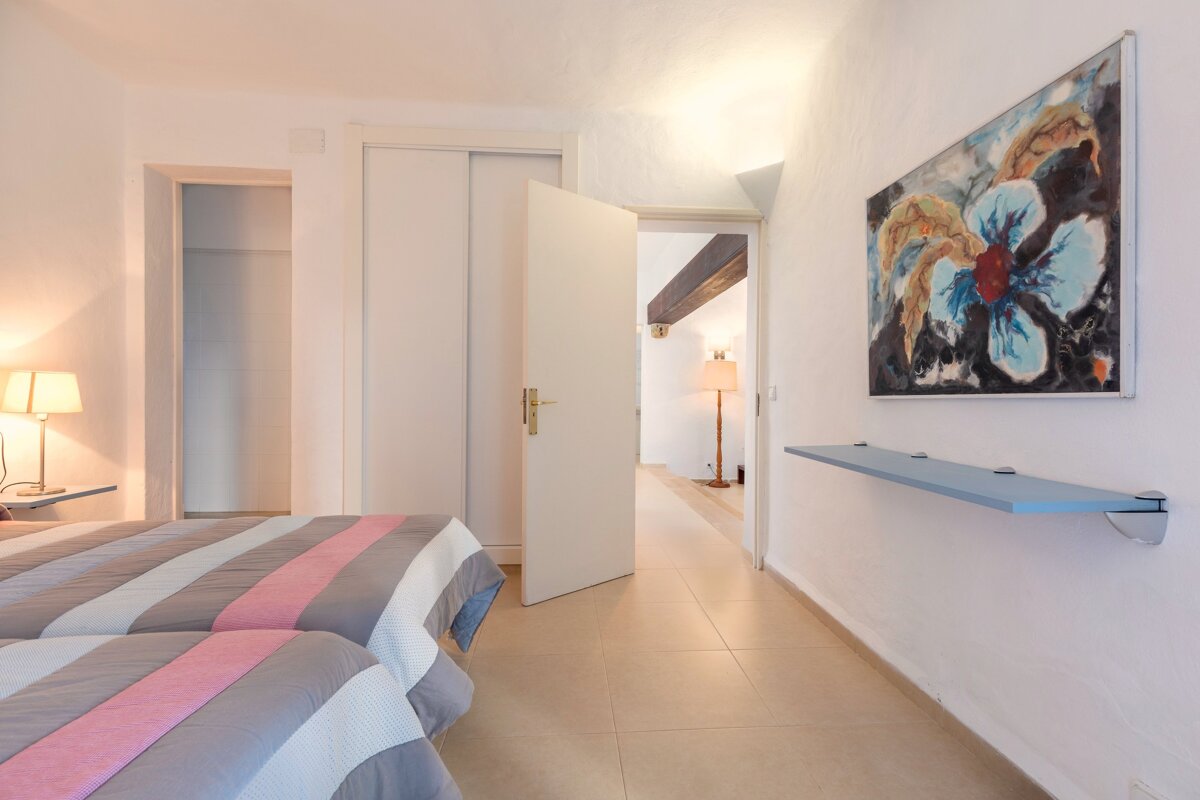 A bedroom with two beds and a painting on the wall