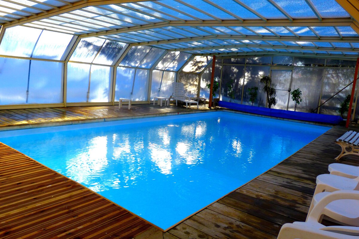 A large indoor swimming pool under a clear roof