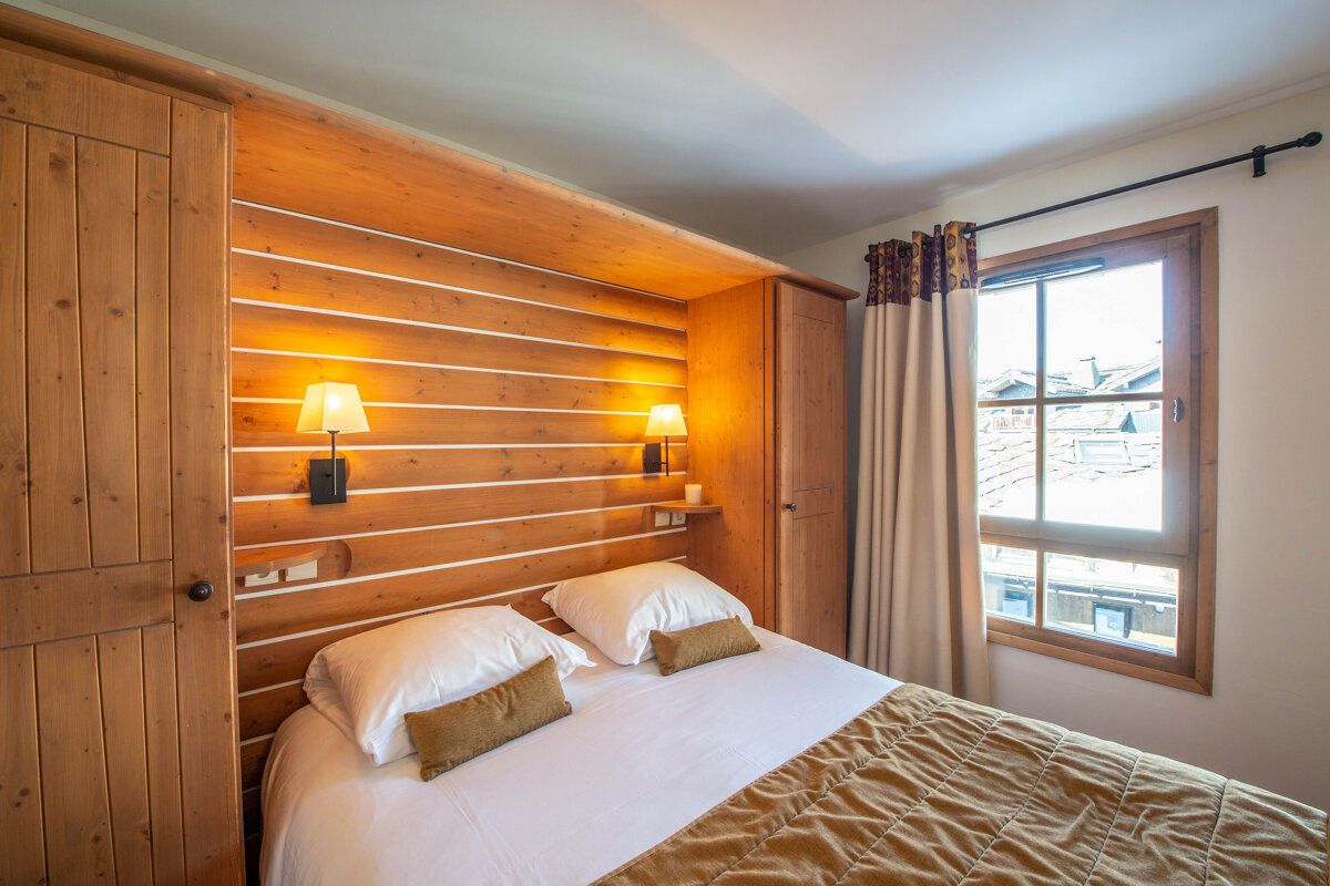 A bedroom with a wooden wall and a bed