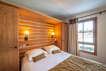 A bedroom with a wooden wall and a bed