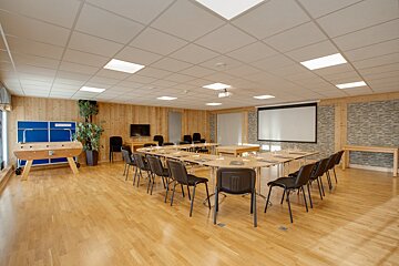 A large room with tables and chairs and a projector screen
