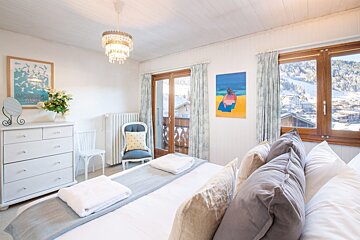 A bedroom with a large bed and a painting on the wall