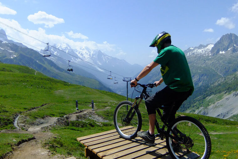 a man stopped at the top of a mountain bike jump