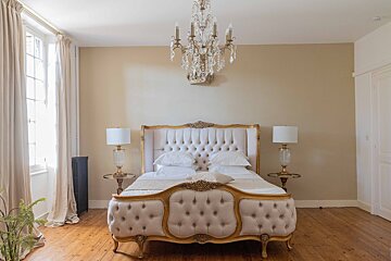 A bedroom with a bed and a chandelier hanging from the ceiling