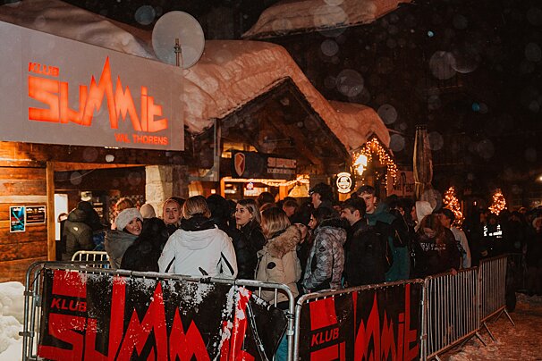 A group of people standing in front of a club called summit