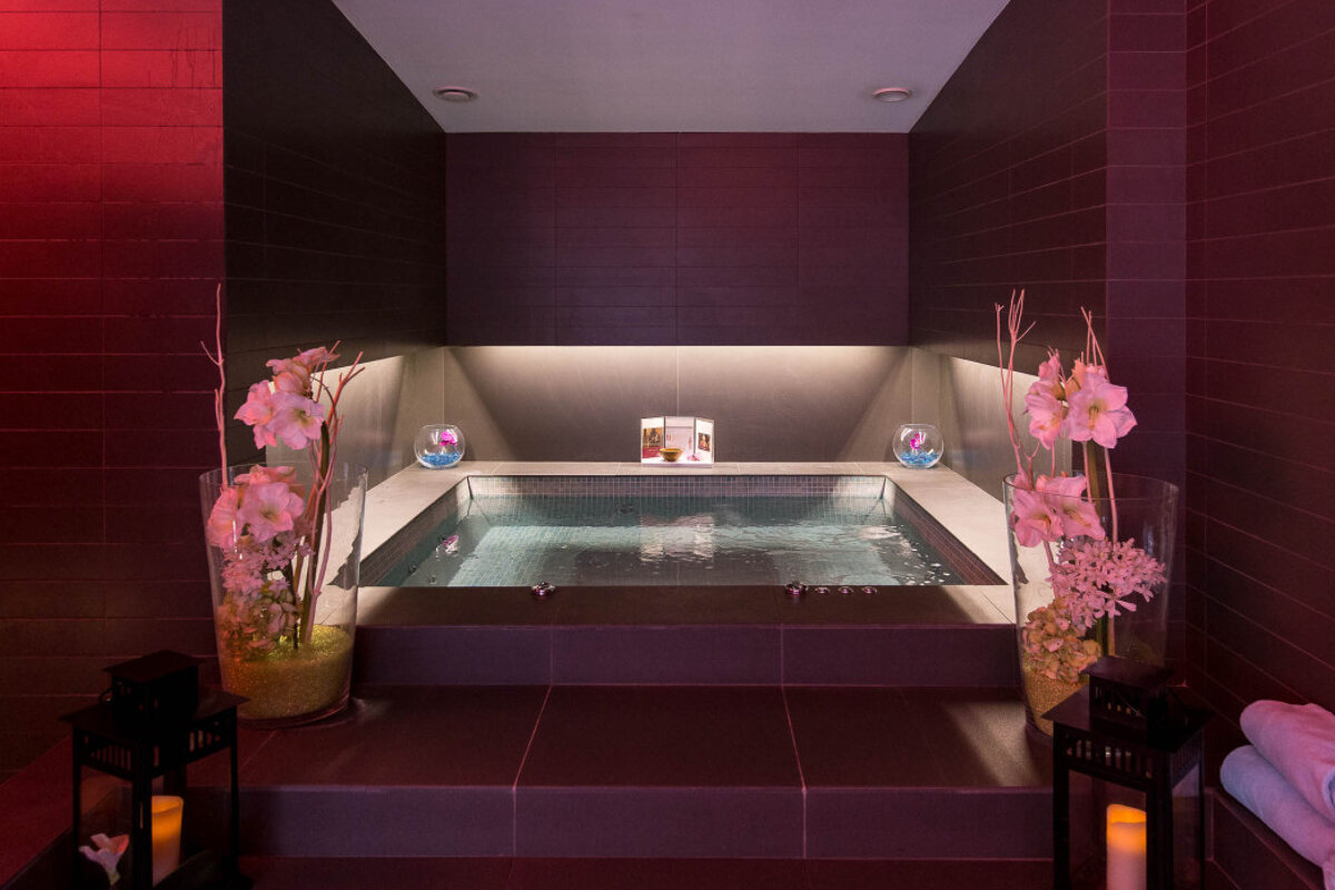 A bathtub in a room with flowers and candles
