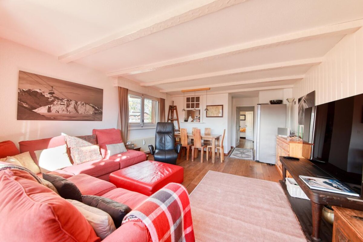 A living room with a red couch and a black chair