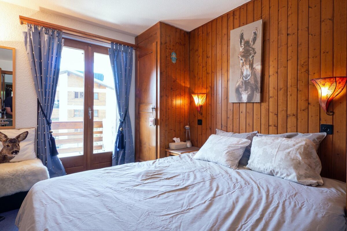A bedroom with a painting of a donkey on the wall above the bed
