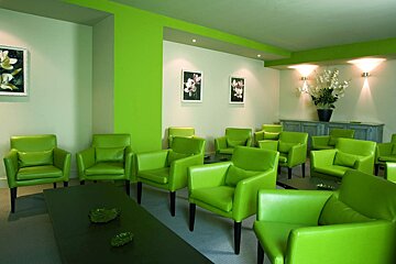 A room with green chairs and flowers on the wall