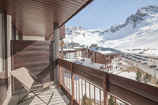 A chair sits on a balcony overlooking snowy mountains